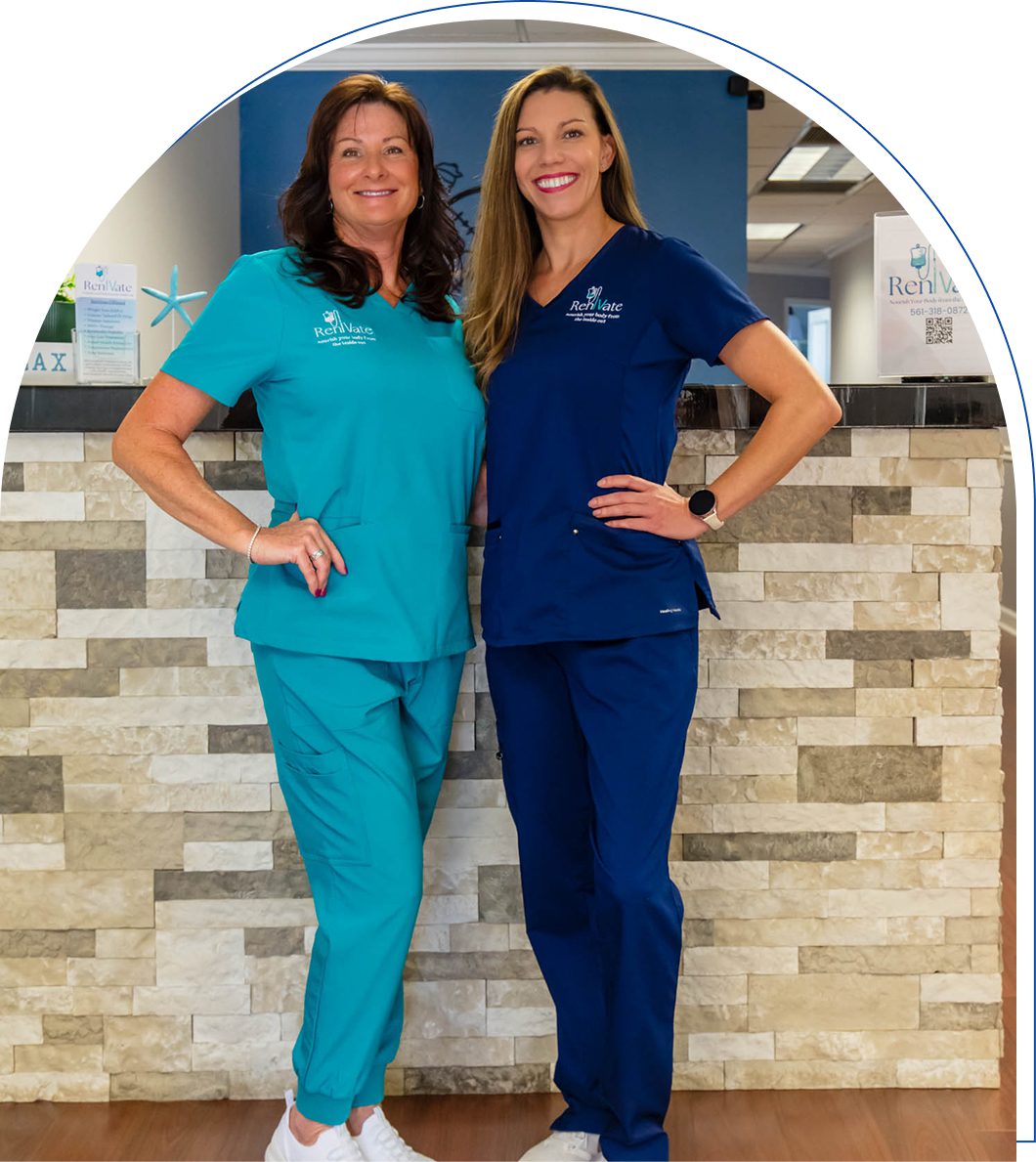 Two women in scrubs standing together indoors.