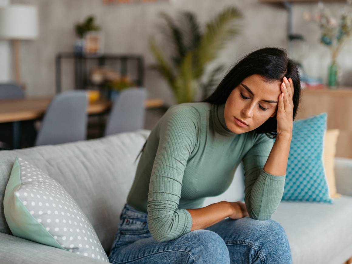 Woman sitting on couch, looking stressed.