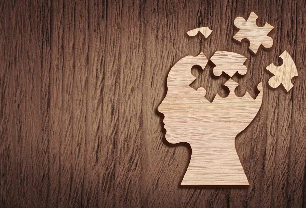 Wooden head silhouette with missing puzzle pieces.