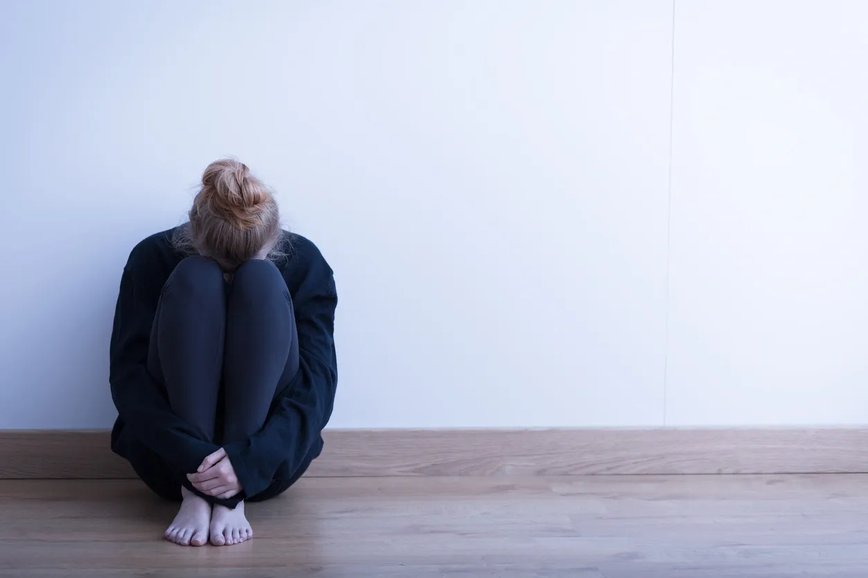 Person sitting alone in a corner.