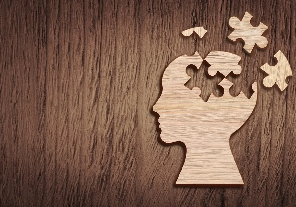 Wooden head silhouette with missing puzzle pieces.